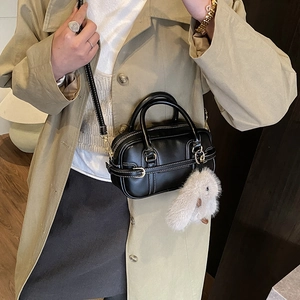 Detail of black pillow bag with white contrast stitching and a plush rabbit charm