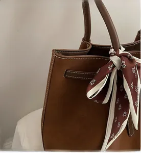 Detail of brown faux suede tote bag with contrast stitching and panda print scarf