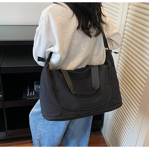 Model wearing a large black waterproof duffel bag for travel, gym, and business use