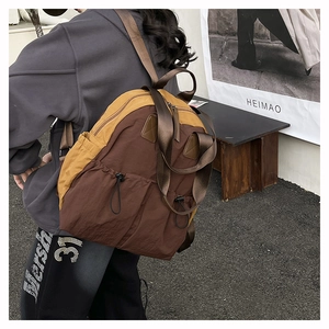 Close-up of side drawstring pocket on retro nylon backpack with color-block design