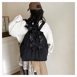 Detailed view of black nylon backpack with drawstring side pockets and adjustable straps