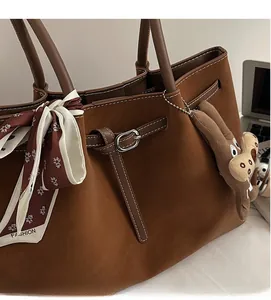 Detail of dark brown faux suede tote bag with plush charm and silk scarf accessory