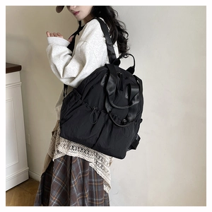 Detail view of black waterproof nylon backpack featuring side drawstring pockets and top handles