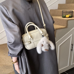 Chic cream white crossbody pillow bag with cute plush rabbit pendant on a model