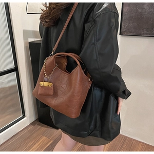 Détail latéral du grand sac seau vintage marron avec mini pochette décorative et chaîne dorée