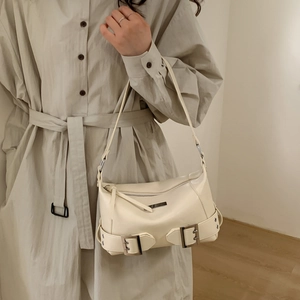 Detail of a beige leather underarm bag featuring silver metal buckles and zipper closure