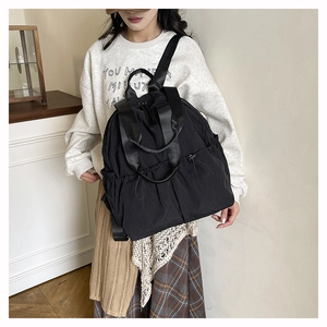 Detail of waterproof black nylon backpack showing side drawstring pocket and shoulder strap