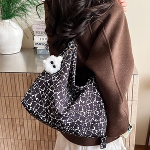 Détail d'un sac cabas à pois noirs et blancs avec un pendentif peluche monstre blanc