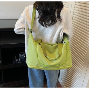 Close-up of green canvas duffel bag showing webbing handles and adjustable shoulder strap