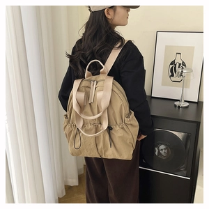 Detail of khaki water-resistant nylon backpack with wide straps and drawstring side pockets