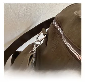 Detail of silver metal hook and zipper on dark olive green suede backpack texture