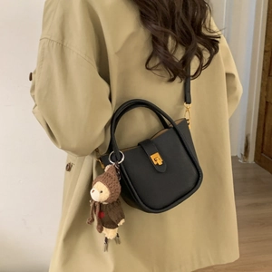 Detail of black lychee grain bucket bag with teddy bear charm and gold metal lock