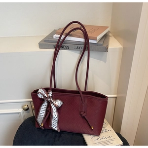 Détail d'un sac cabas tissé bordeaux montrant la texture du cuir et le foulard décoratif