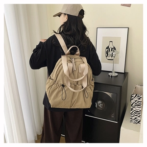 Rear view of khaki waterproof nylon travel backpack shown on model in modern room