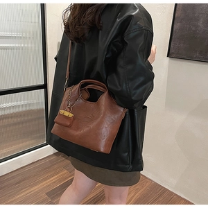 Sac fourre-tout en cuir marron avec pochette et bandoulière porté par un mannequin
