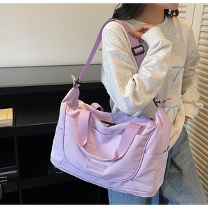 Lavender large capacity travel bag worn on shoulder by model in home setting