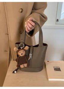 Dettaglio borsa a secchiello in pelle martellata con finiture argento e ciondolo orso