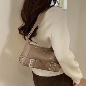Detail view of vintage beige underarm bag with leather straps and silver buckles