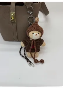 Détail d'un pendentif ours beige crocheté à la main avec pull marron sur un sac seau