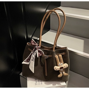 Detail of suede tote bag with silk scarf, plush bunny charm, and metal buckle accents