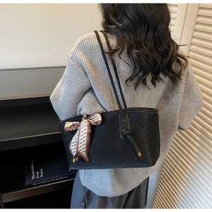 Détail d'un sac cabas tissé noir avec un foulard géométrique sur la poignée