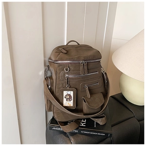Detail of dark brown faux leather backpack showing multiple zipper pockets and texture