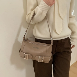 Detail of warm khaki underarm bag with silver buckles worn as a minimalist shoulder bag