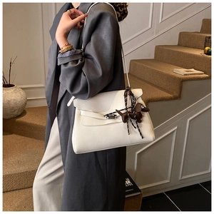 Detail of white leather briefcase with silk scarf wrap and dog charm on stairs