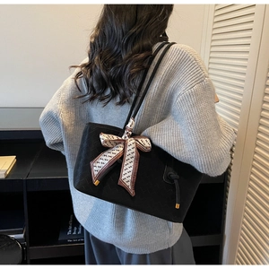 Détail d'un cabas noir tissé avec un foulard en soie géométrique noué à l'anse