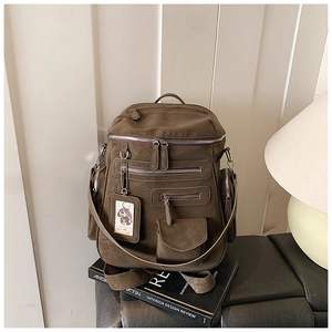 Detail view of olive brown travel backpack with multi-zipper pockets and cartoon accessory