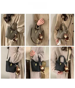Vue détaillée du sac seau minimaliste avec fermoir métallique et charm ours en peluche