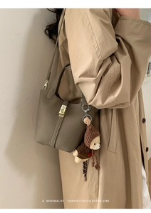 Détail du sac seau en cuir taupe avec fermoir doré et breloque ours en peluche marron