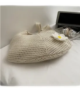 Detail of soft cream knitted tote bag with a white 3D flower and yellow center