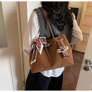 Detail of a brown suede tote bag with a floral fashion scarf and a cute rabbit charm