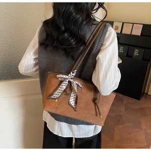 Gros plan sur un cabas en daim marron avec motifs gaufrés et ruban décoratif chic