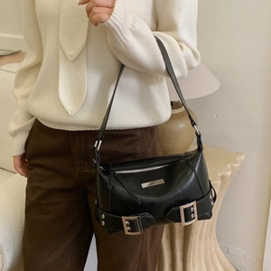 Detail of black glossy leather underarm bag with silver buckles and zipper on a model