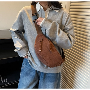 Détail d'un sac bandoulière marron avec texture mate et tirette de zip tissée à la main