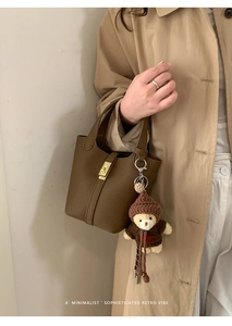 Détail du sac seau en cuir litchi marron avec fermoir doré et breloque petit ours