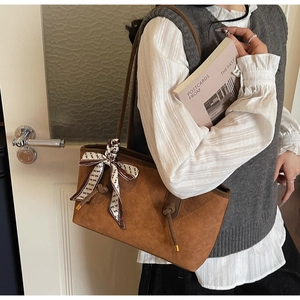 Détail du sac cabas marron tissé avec un foulard décoratif en soie sur la bandoulière