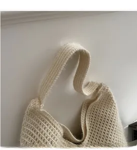 Close-up of the wide reinforced woven handle on a beige oversized knitted tote bag