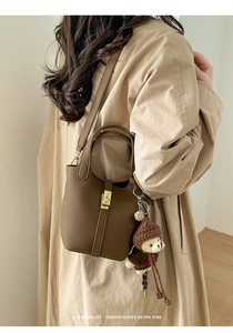 Détail du sac seau en cuir grainé marron foncé avec fermoir doré et breloque ours