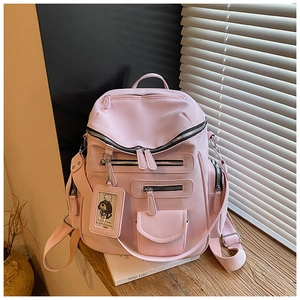 Detailed view of pink nylon travel backpack with multiple pockets and cute cartoon tag