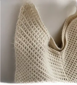 Close-up of beige knit fabric showing soft mohair texture and hollow mesh crochet pattern