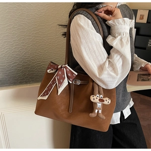Detail of dark brown faux suede tote bag with printed silk scarf and plush bunny charm