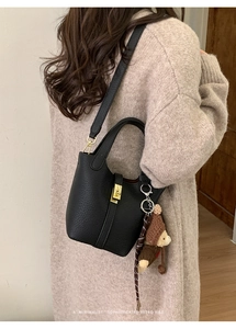 Détail d'un sac seau en cuir grainé noir avec cadenas doré et breloque ours mignon