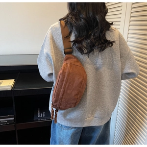 Vue de dos d'un sac bandoulière sport marron minimaliste sur un pull gris décontracté