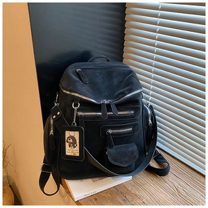 Detail of black multi-pocket backpack with silver zippers and a cute dog charm