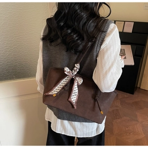 Détail d'un sac cabas marron tissé orné d'un foulard élégant et de finitions métalliques
