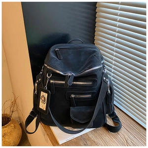 Detail view of a black multi-pocket travel backpack with a cute dog charm and zippers