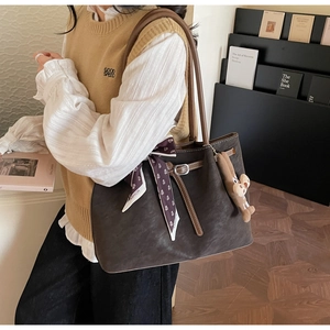 Close-up of suede tote bag featuring a decorative silk scarf and plush cartoon pendant